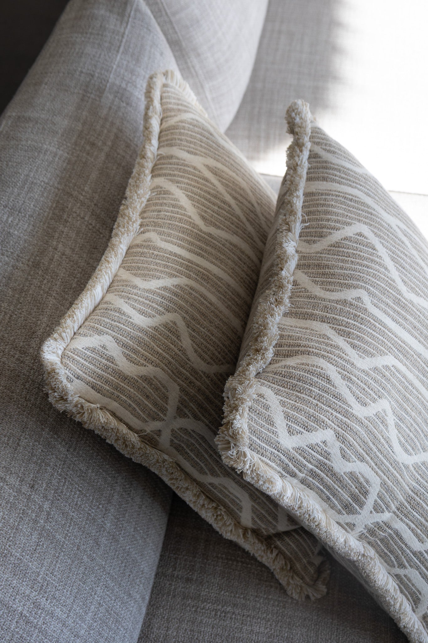 Martin Gabriel Dekokissen Modell Linea auf sofa mit wei kissen vorienander material in leinen wolle beige und helle unregelmässige streifen schatten auf sofa