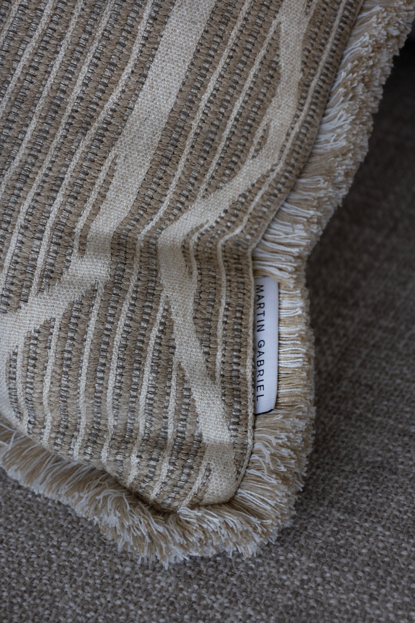 Martin Gabriel Logo auf Kissen modell linea dekokissen clos up beige mit streifen auf sofa