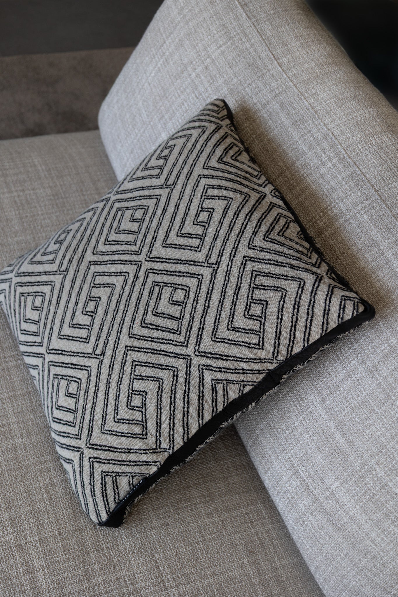 Martin gabriel Deko Zierkissen Modell Noir labyrith seitliche ansicht auf sofa beige kissen mit grauer leinen struktur und labyrinh design 
