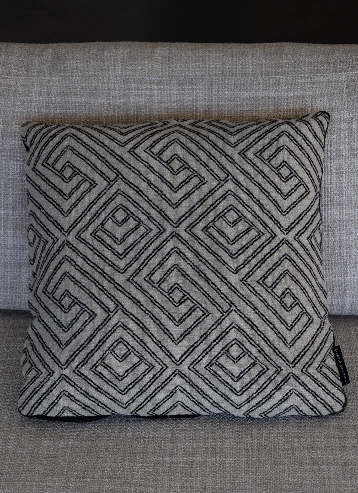 Martin Gabriel dekokissen modell Noir Labyrinth auf ofa, grauen leinen mit labyritnth design in schwarz auf beige grauem sofa 