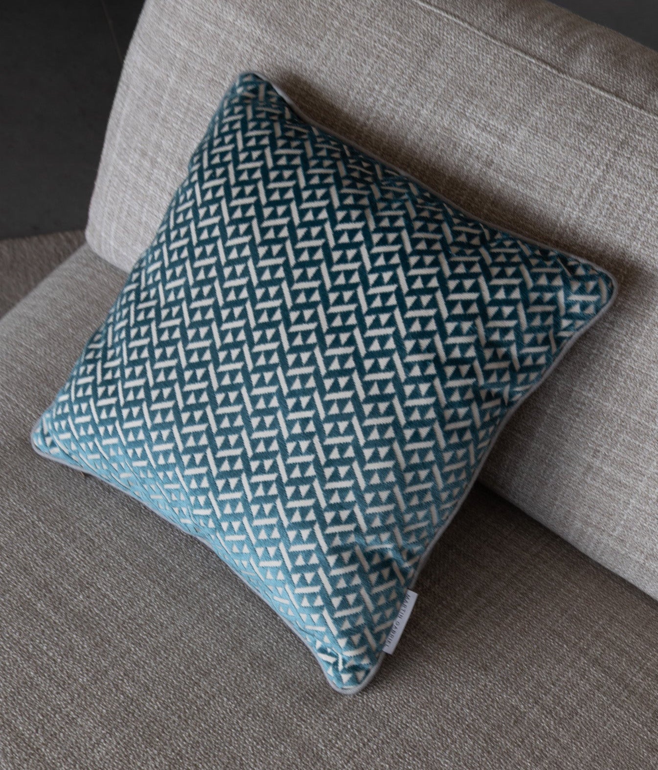 Martin Gabriel Deko Kissen Azzuro auf Sofa seitenasicht in blau mit grauem rücken und dreiecken in velour auf sofa von oben auf beigem hintergund textil vom sofa 