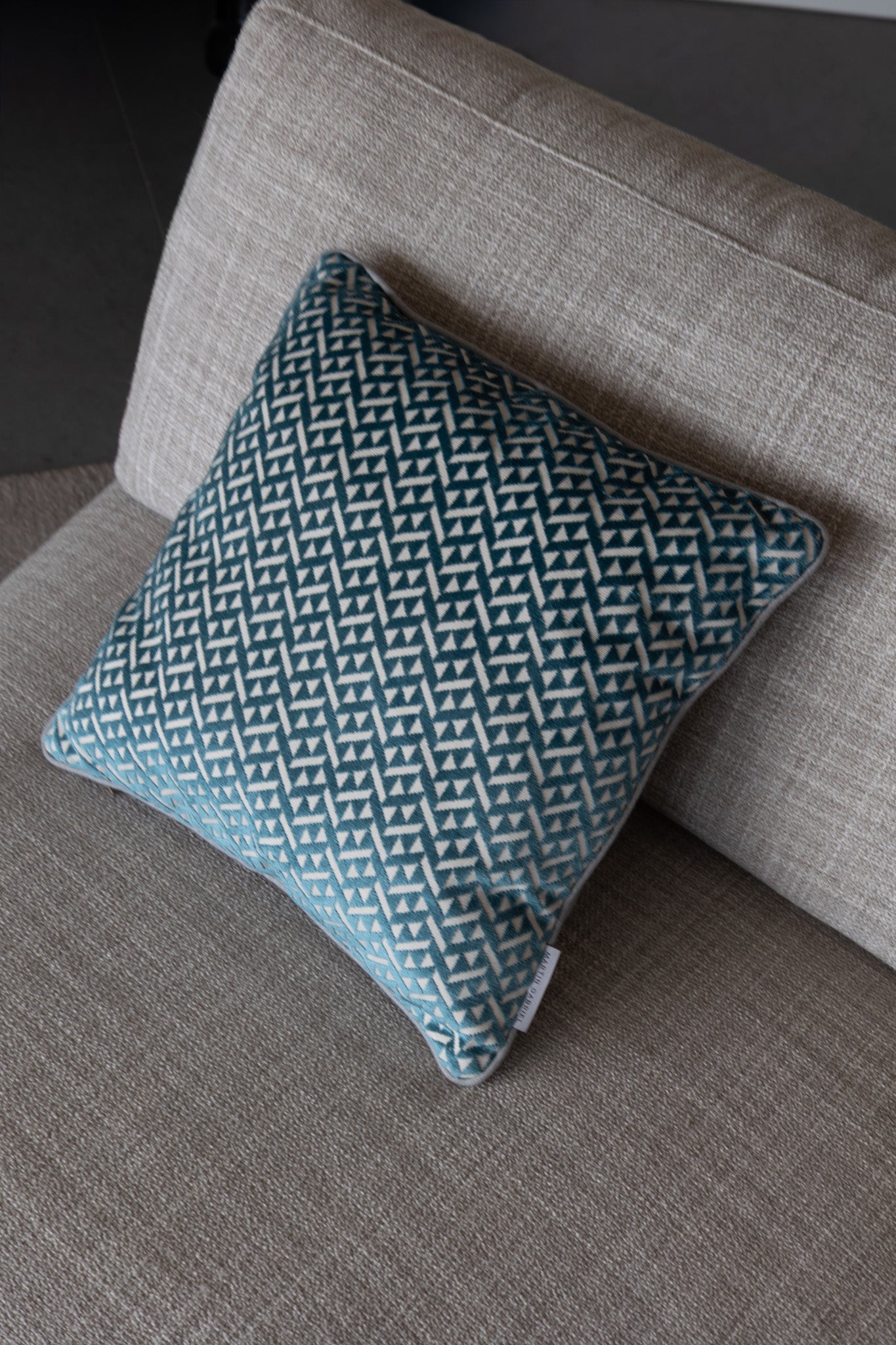 Martin Gabriel Deko Kissen Azzuro auf Sofa seitenasicht in blau mit grauem rücken und dreiecken in velour auf sofa von oben auf beigem hintergund textil vom sofa 