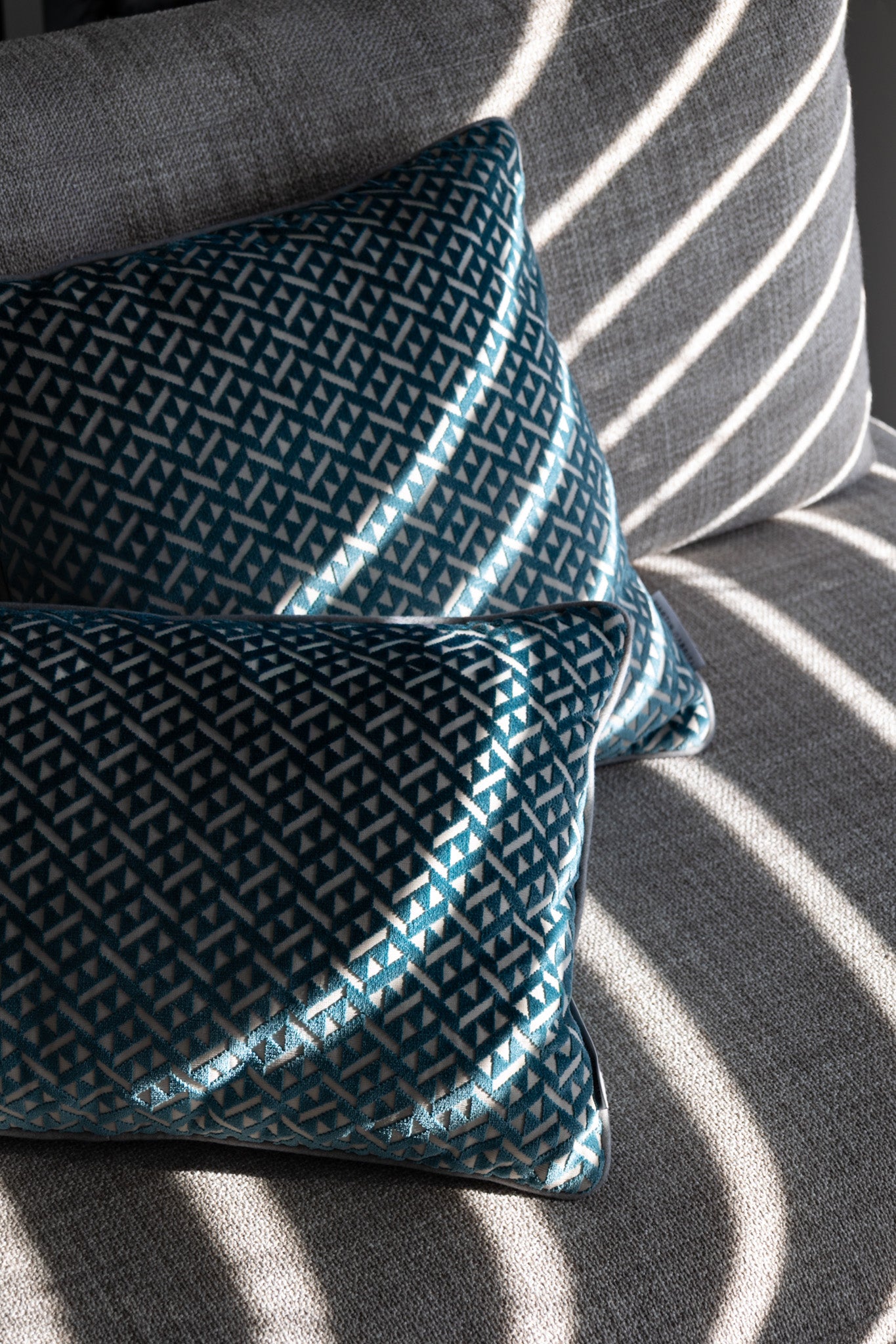 Martin Gabriel zwei Deko Kissen Azzuro auf Sofa seitenasicht in blau mit grauem rücken und dreiecken in velour 