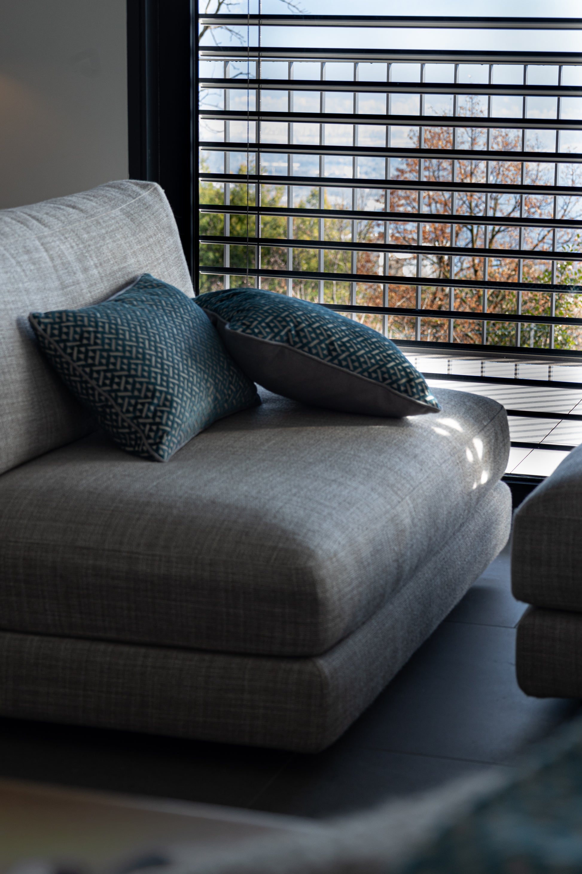 Martin Gabriel zwei Deko Kissen Azzuro auf Sofa seitenasicht in blau mit grauem rücken und dreiecken in velour 
