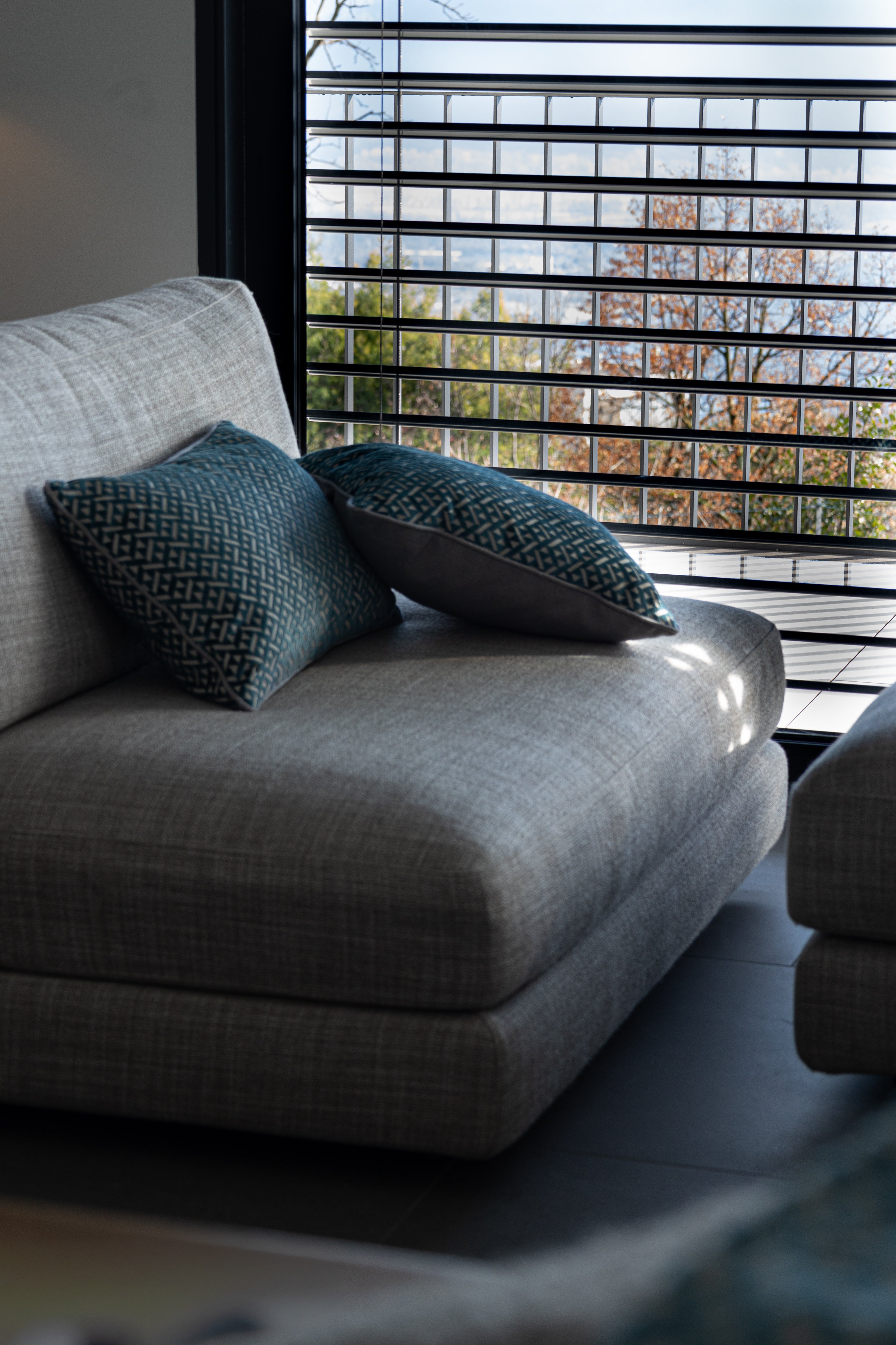 Martin Gabriel zwei Deko Kissen Azzuro auf Sofa seitenasicht in blau mit grauem rücken und dreiecken in velour 