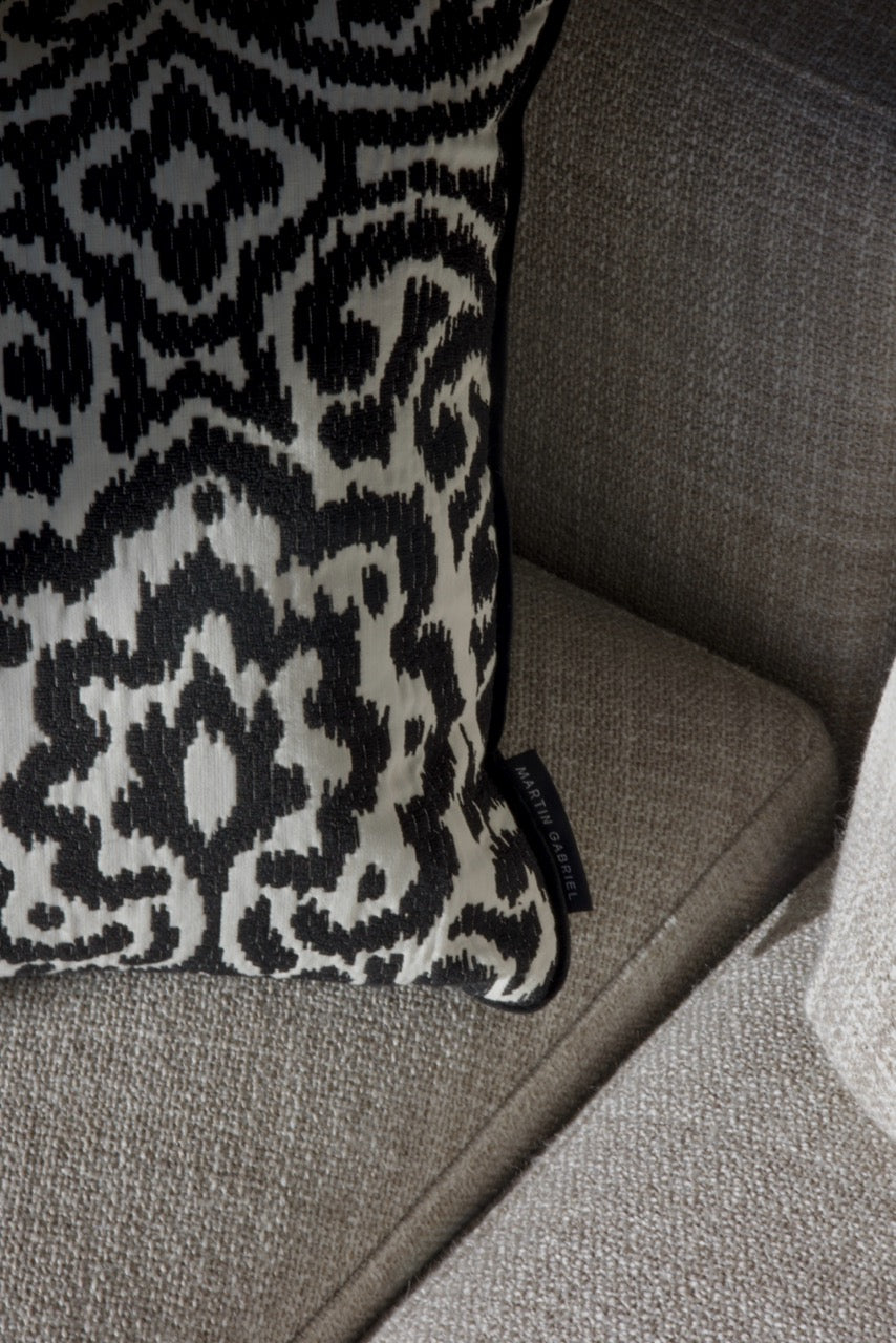 Martin Gabriel Designkissen Modell Relief Noir schwarz weisse relief struktur mit ornament muster auf sofa in grau nahaufnahme 