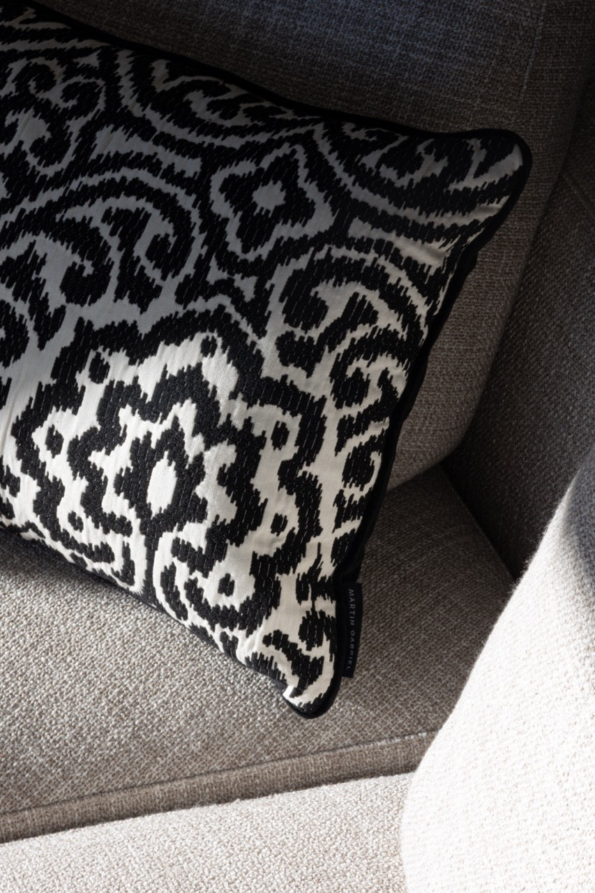 Martin Gabriel Designkissen Modell Relief Noir schwarz weisse relief struktur mit ornament muster auf sofa in grau mit label martin gabriel