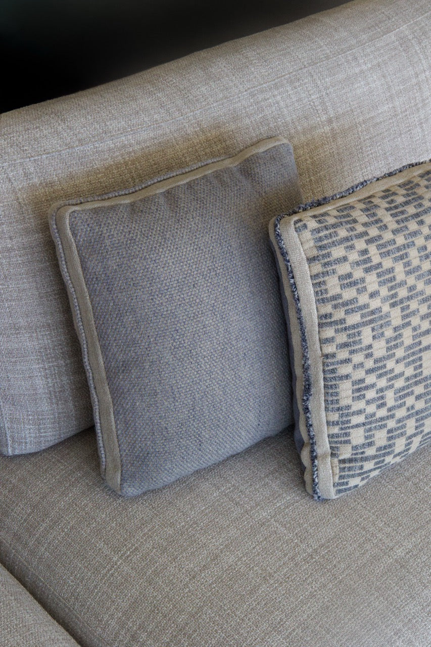 Martin Gabriel Dekokissen Blue Wave Leinen sichtbar  zwei dieser Kissen eines mit struktuer und das andere in uni blau mit ordüre und keder in blau auf beigem sofa 