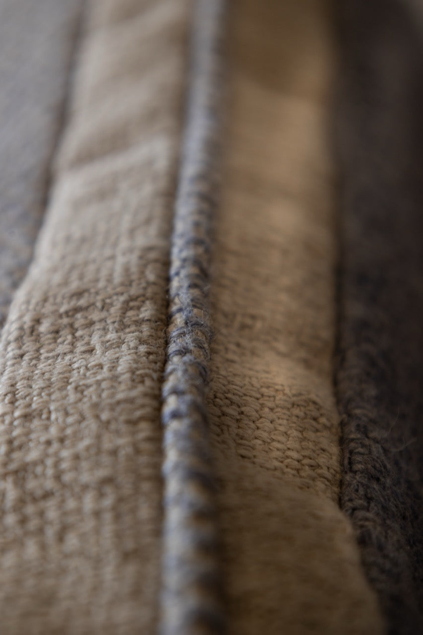 Martin gabriel Zier kissen Modell Blue Wave Calm nahaufnahme von der bordüre in beige leinen mit bleuenm keder in leinem struktur sichtbar 