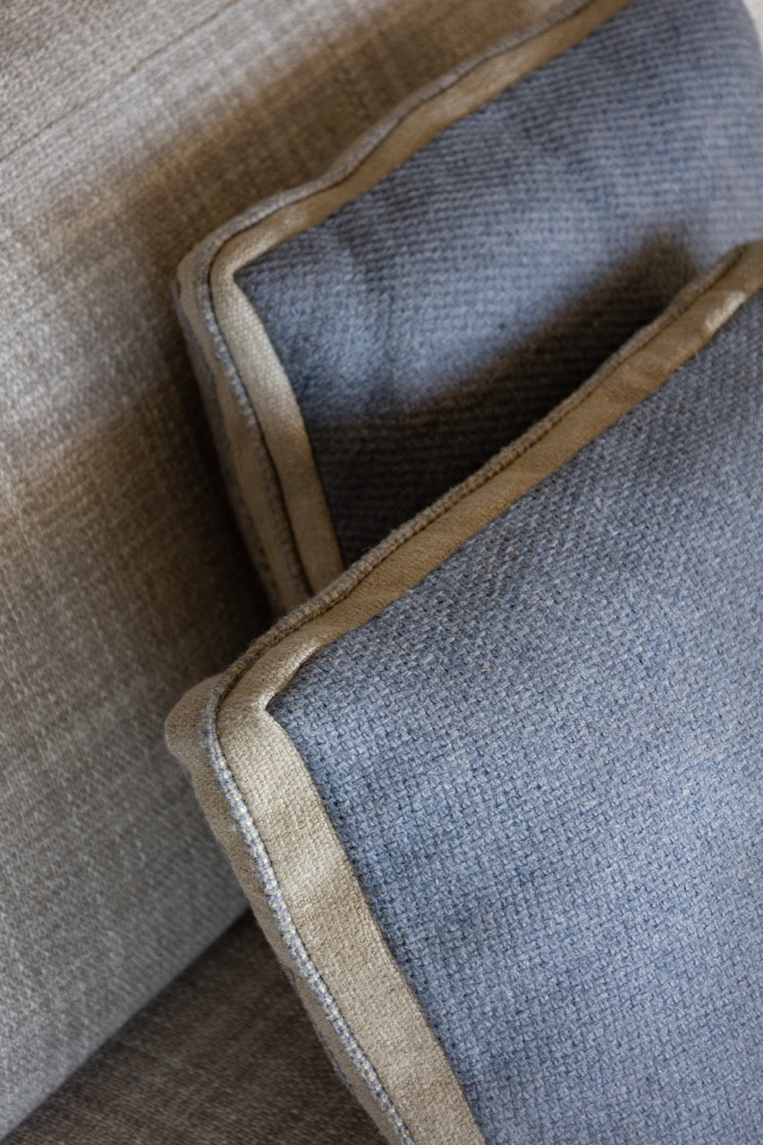 Martin Gabriel Zierkissen modell Blue Wave calm zwei kissen auf sofa rücksiete sichtbar in blau leinen mit beiger bordüre auf sofa seitlich sichtbar 