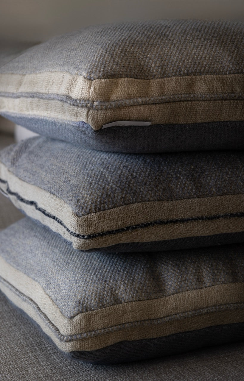 Martin Gabriel Dekokissen Modell Blue Wave Calm gestapelt  drei kissen in selben Material und struktiur nahaufnahme in bleu mit beiger bordüre und blauen keder in leinen 