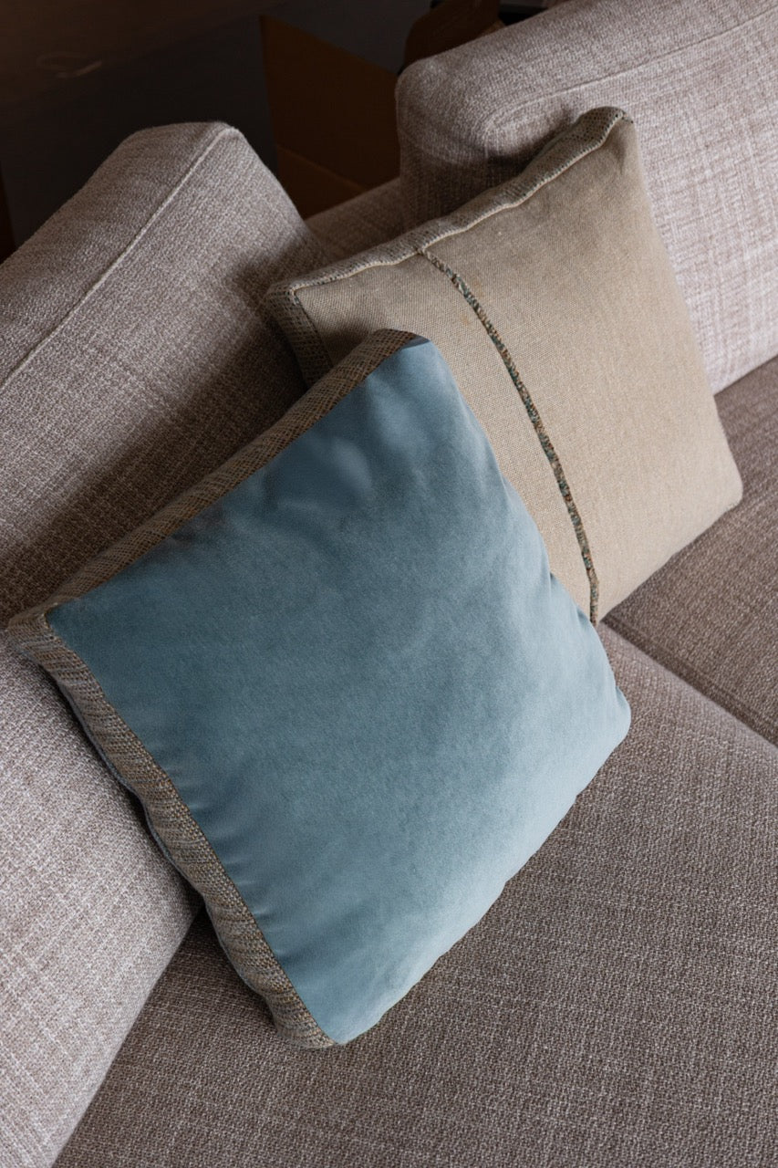 Martin-Gabriel Velour Dekokissen in Blau mit Leinenrückseite und strukturiertem Mittelstreifen auf hellem Sofa
