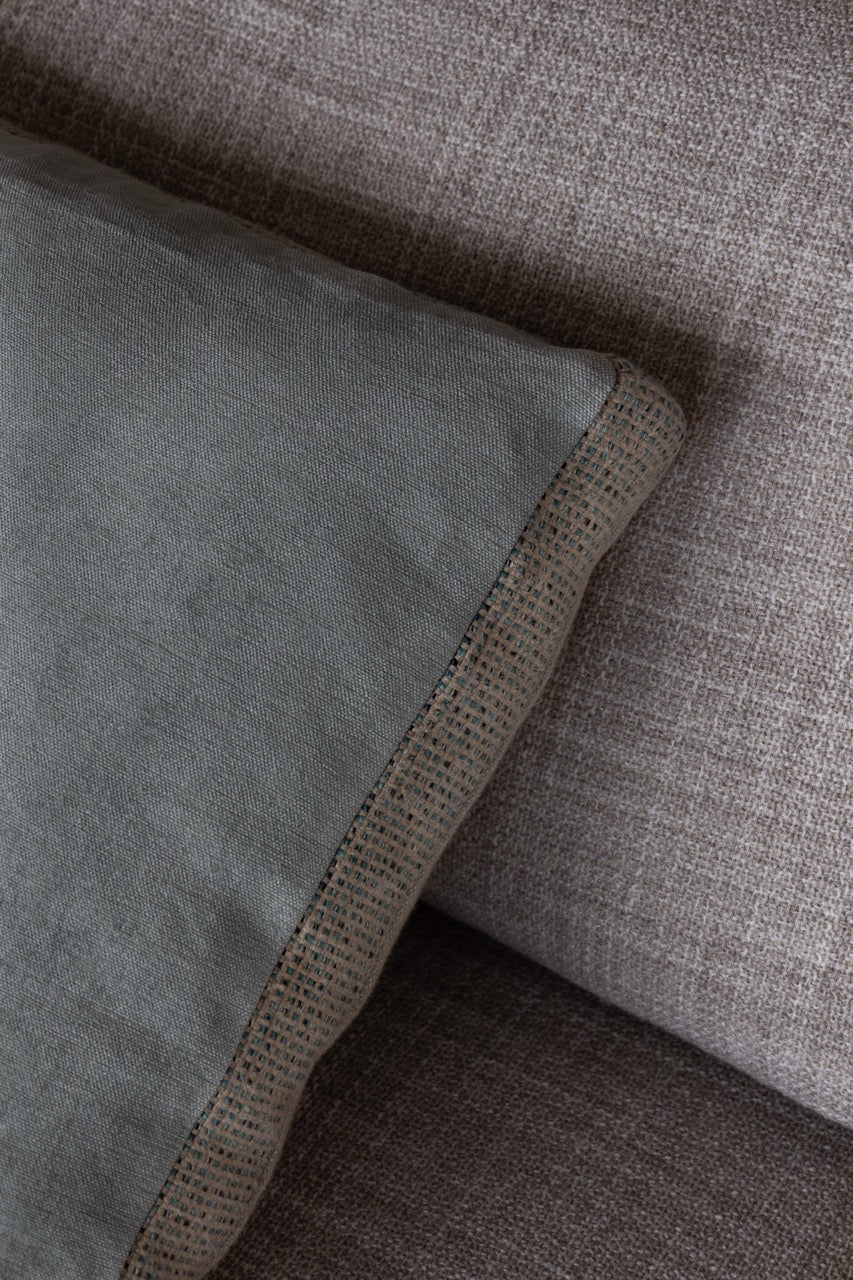 Martin-Gabriel Leinen Dekokissen Blue Ligne 02 mit Mittelband und feiner Fransenkante in Naturton und hellblauer Rückseite auf Sofa
