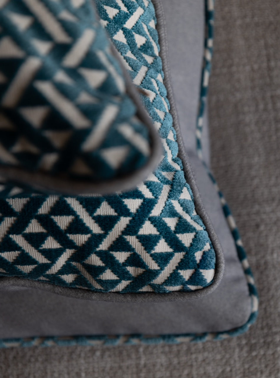 Martin Gabriel Dekokissen Modell Azzuro auf sofa, drei überienandergestapelt von oben in blauen veloru mit muster in dreiecken 