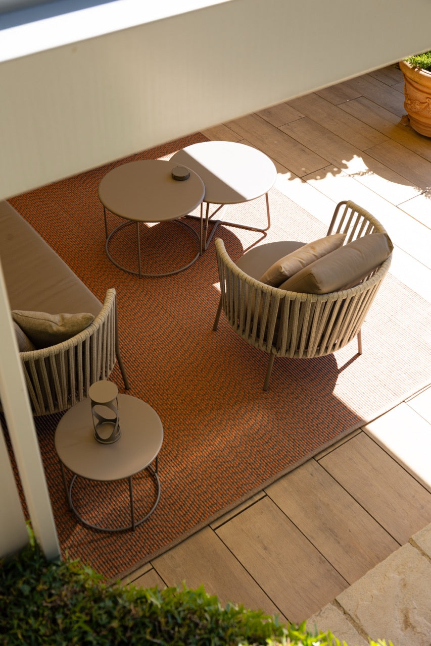 Outdoor teppich mit gewebter struktur in orange und taupe auf sonniger Terrasse