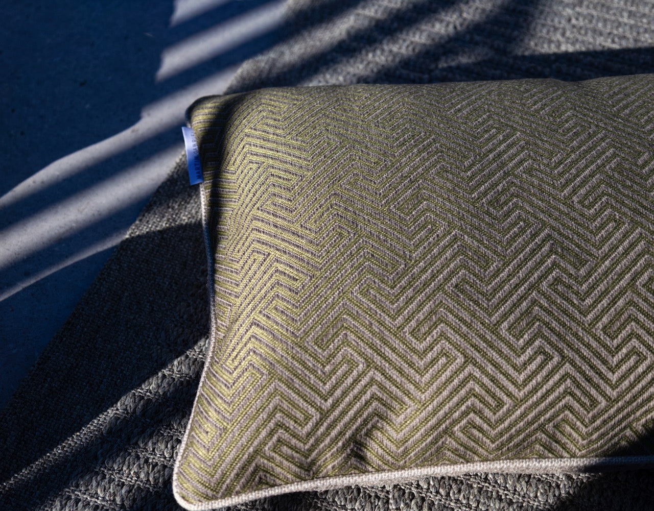 nahaufnahme outdoorkissen mit geometrischen muster in grün auf teppich 