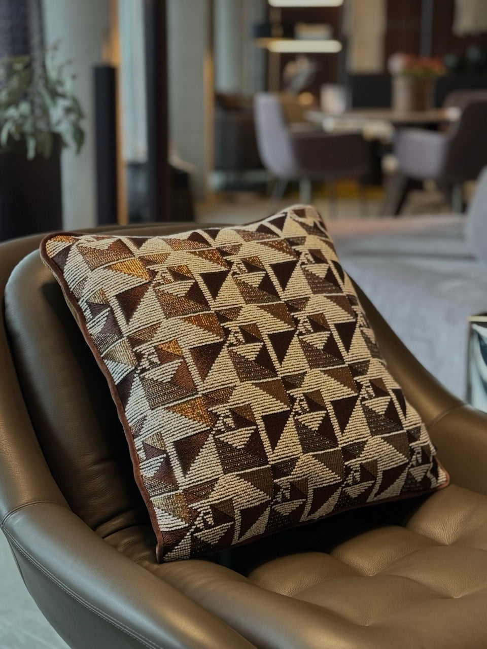Martin Gabriel Designkissen Modell geometrie in goldbraunen design auf braunen ledersessel in showroom 