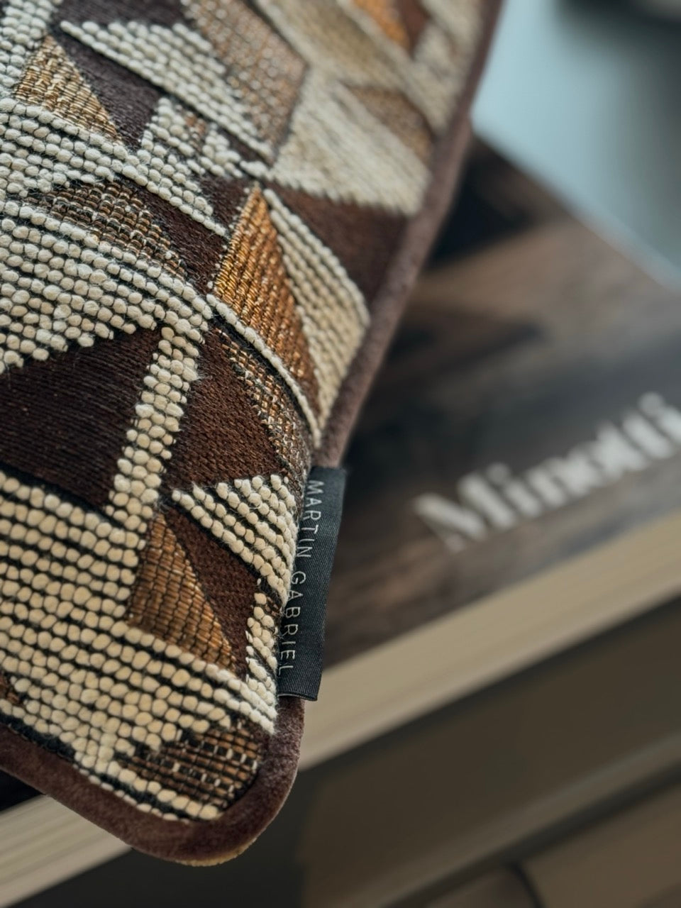 martin gabriel Designkissen Modell geometrie auf einem Buch ald nahnsicht mit geometrishcen deisgn und gildigen braunen farben 