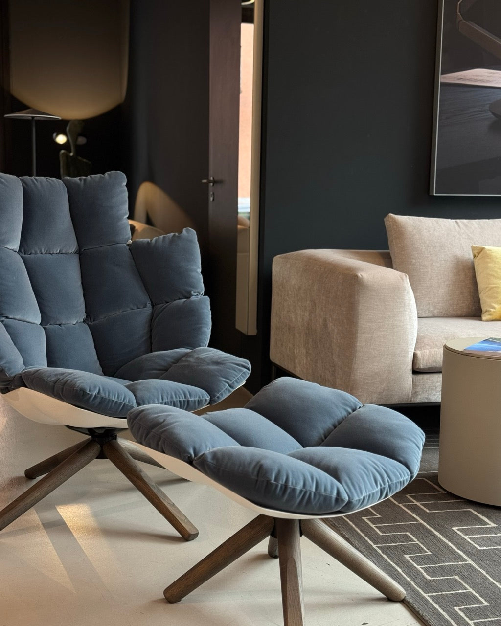 Modernes Interieur mit blauem lounge-Sessel und Hocker n Velours, kombiniert mit wohnlichen Akzenten.