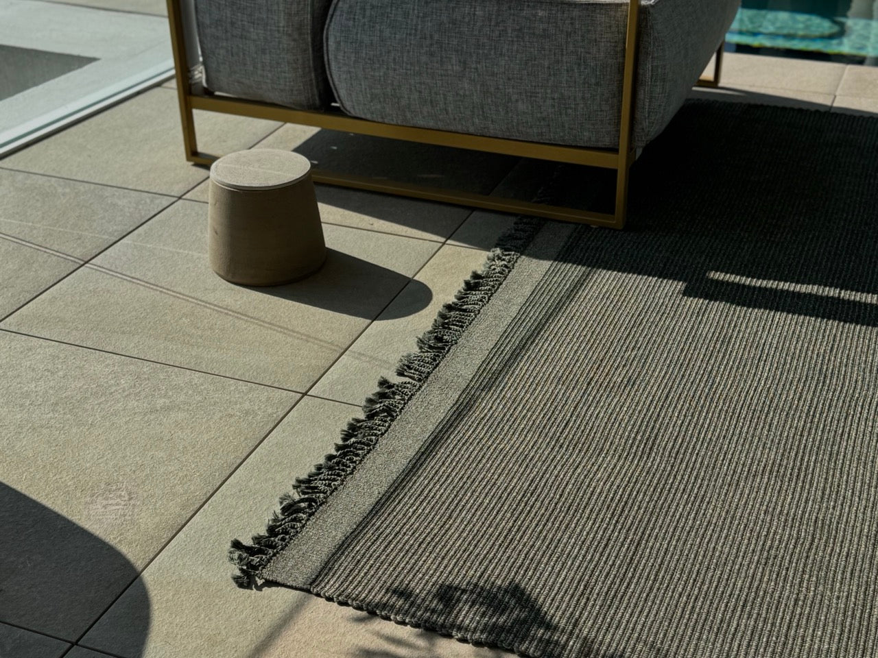 Outdoor teppich mit fransen auf grosser terrasse in einem grün grau 