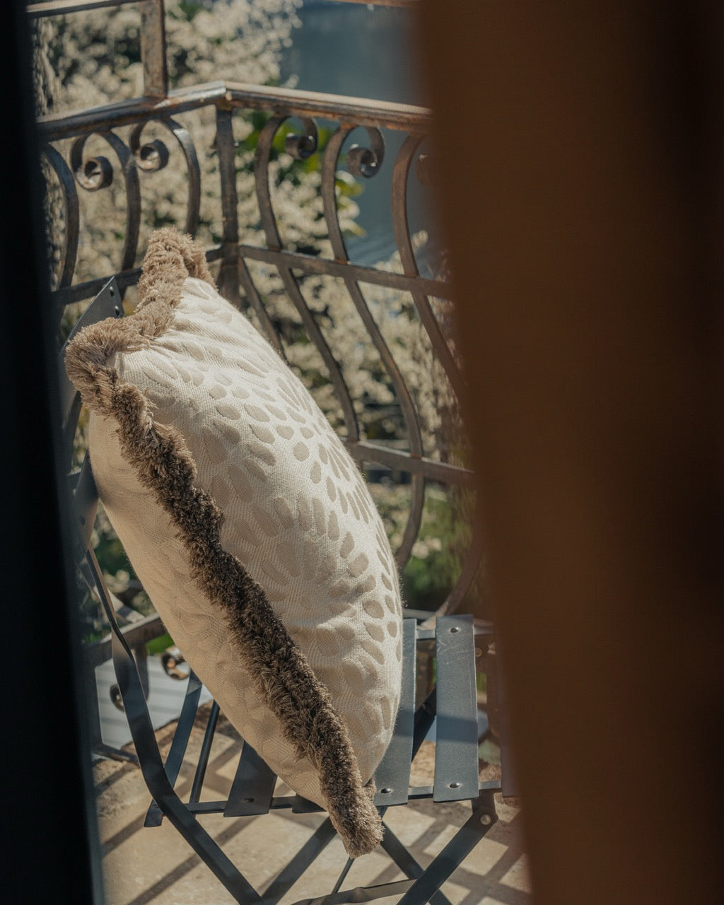 Outdoor Kissen auf Balkon in beige mit Fransen und lanschaft im Hintergrund 
