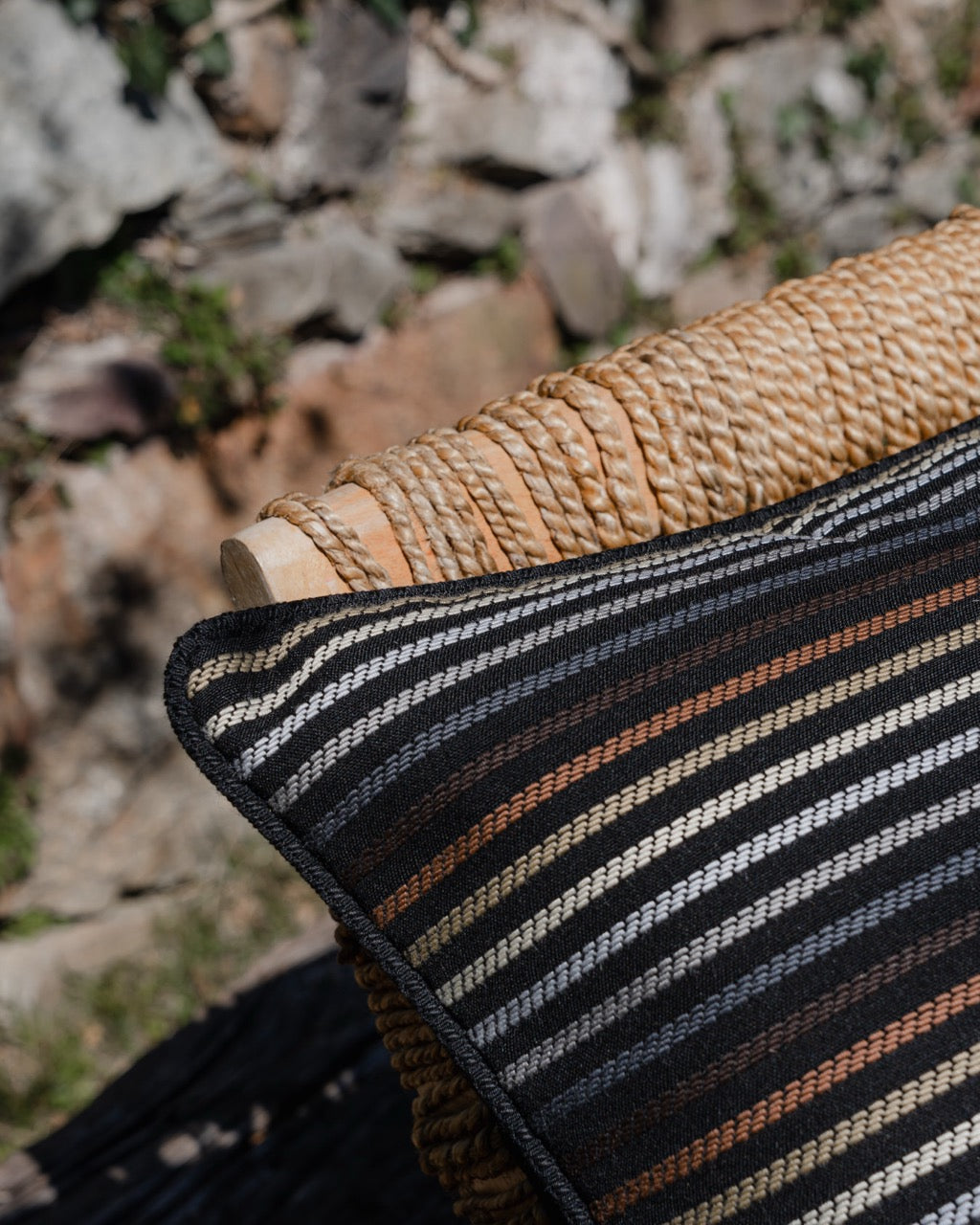 Detailaufnahme Outdoor Kissen mit dezenten Erdfarbenen Streifen und Hintergrund schwarz