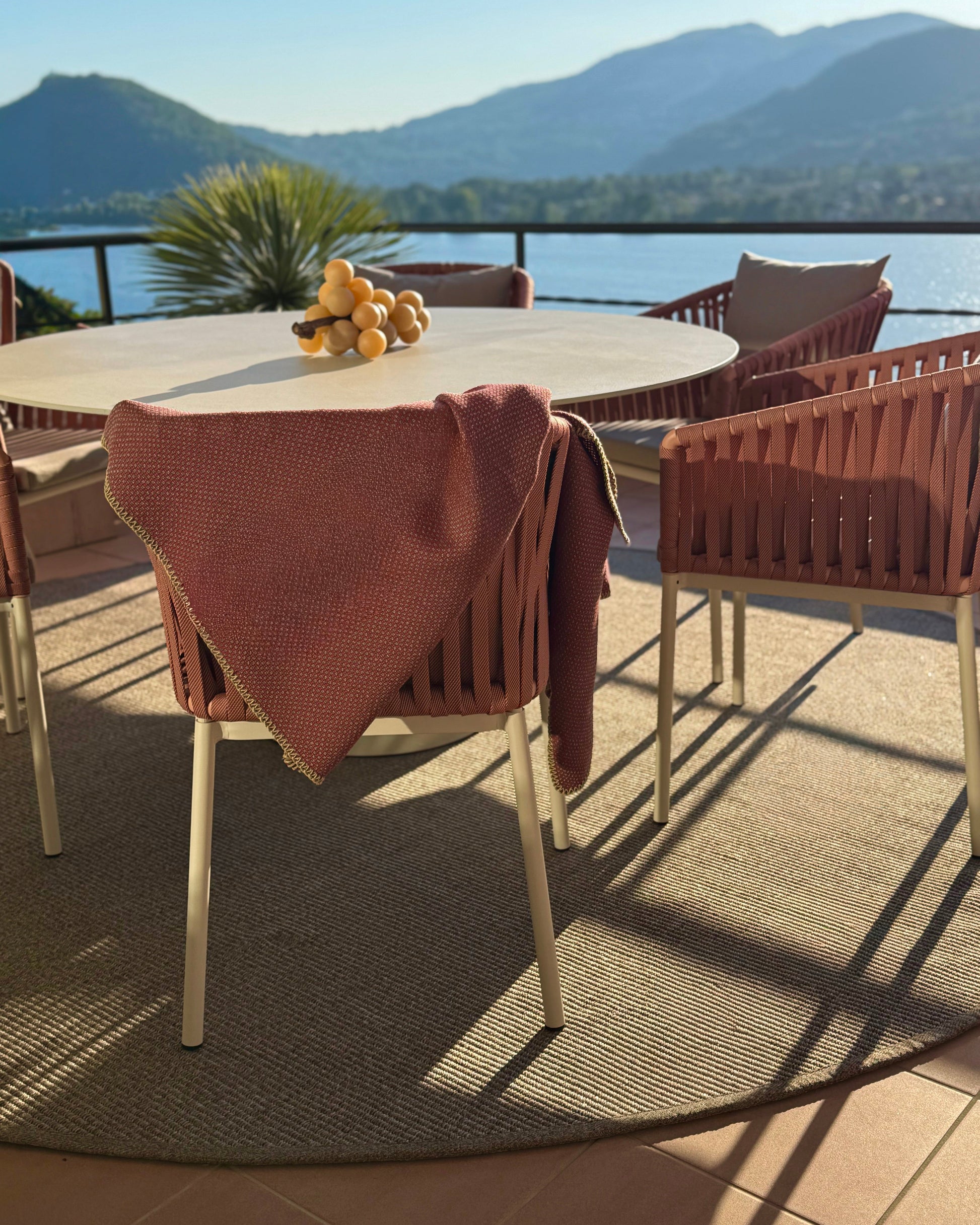 Outdoor Teppich in Tabak farben uf Terrasse , runder Teppich mit Tisch und Stühlen und Seeblick 