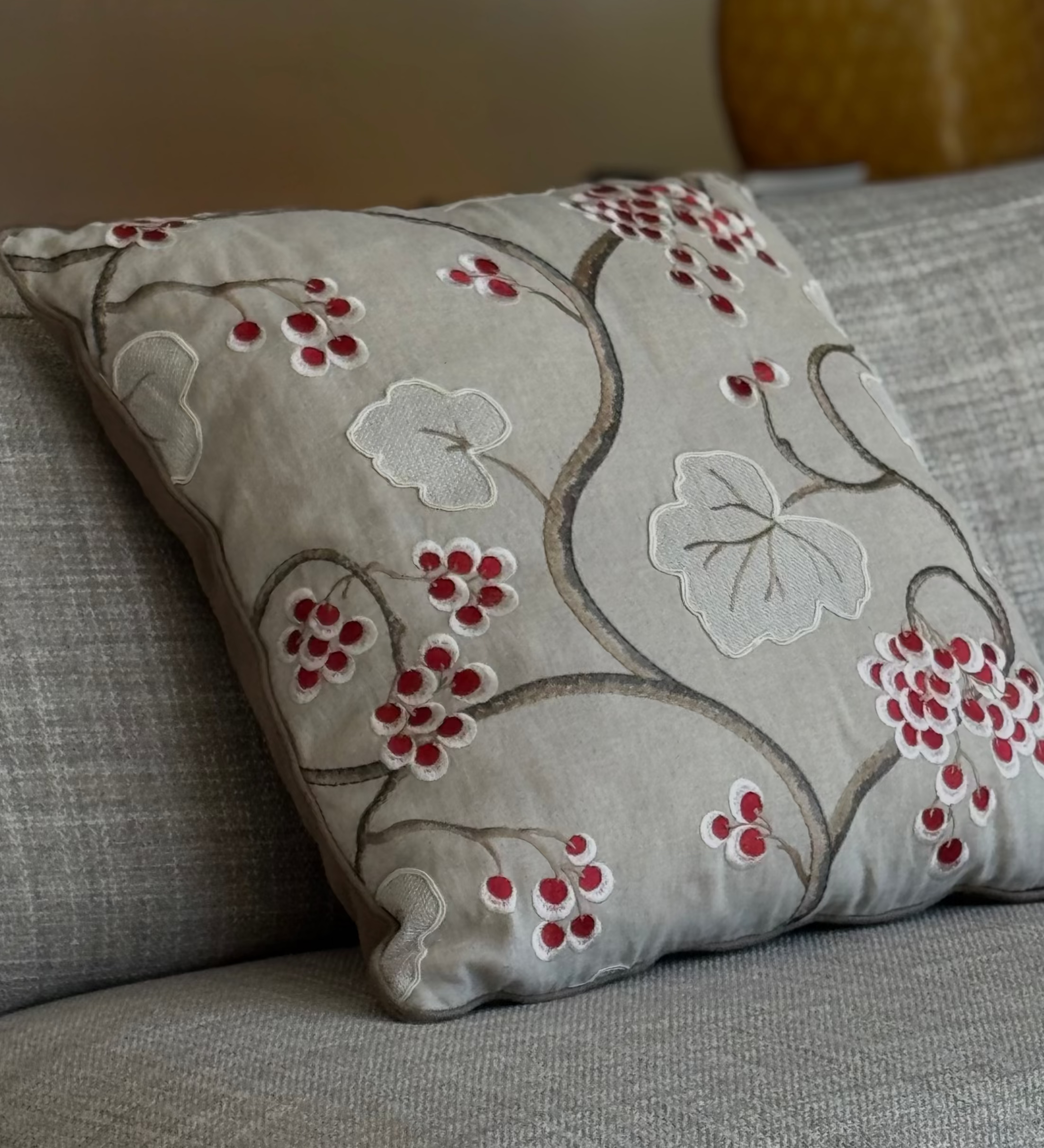 Martin Gabriel deko kissen modell leaf & berry mit floraler stickerei in natur - und beigetönen auf grauem sofa