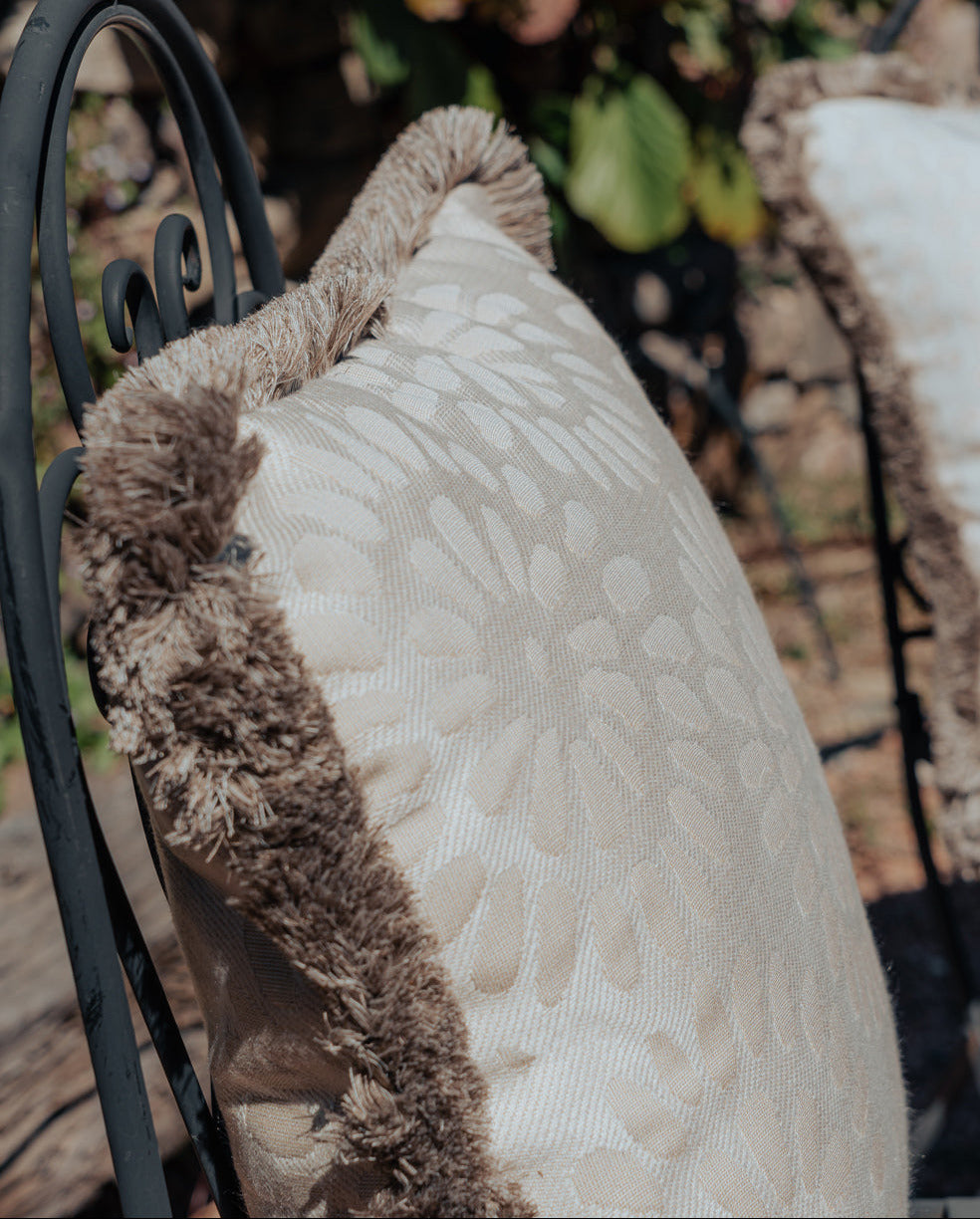Outdor Kissen beige mit fransen auf stuhl im garten 
