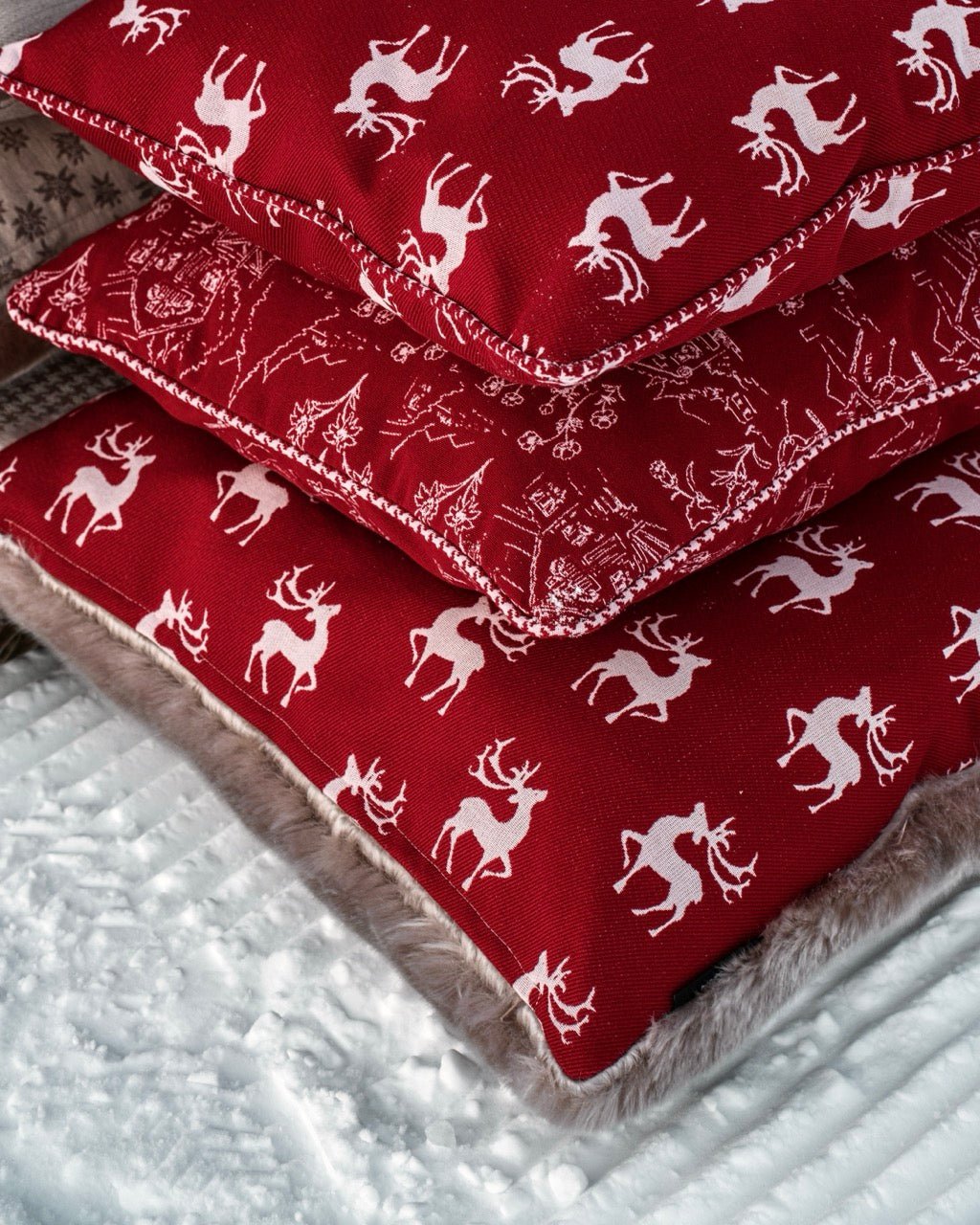 Martin Gabriel Indoor Kissen Chalet Kollektion Modell Alpine redstag im schnee mit zwei weiteren Chalet kissen im schnee übereinander liegend 