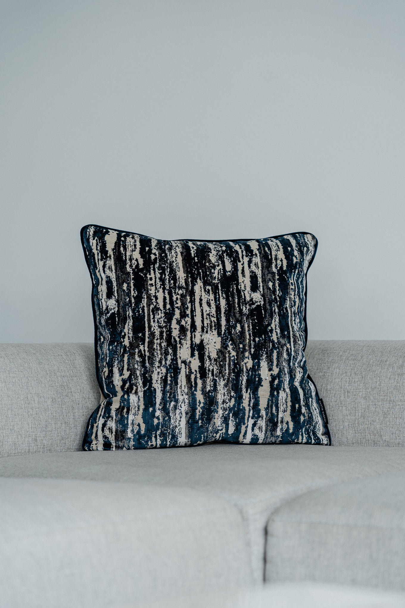 Dekokissen Cascade Blue 60x60 cm auf hellgrauem Sofa – Vorderansicht