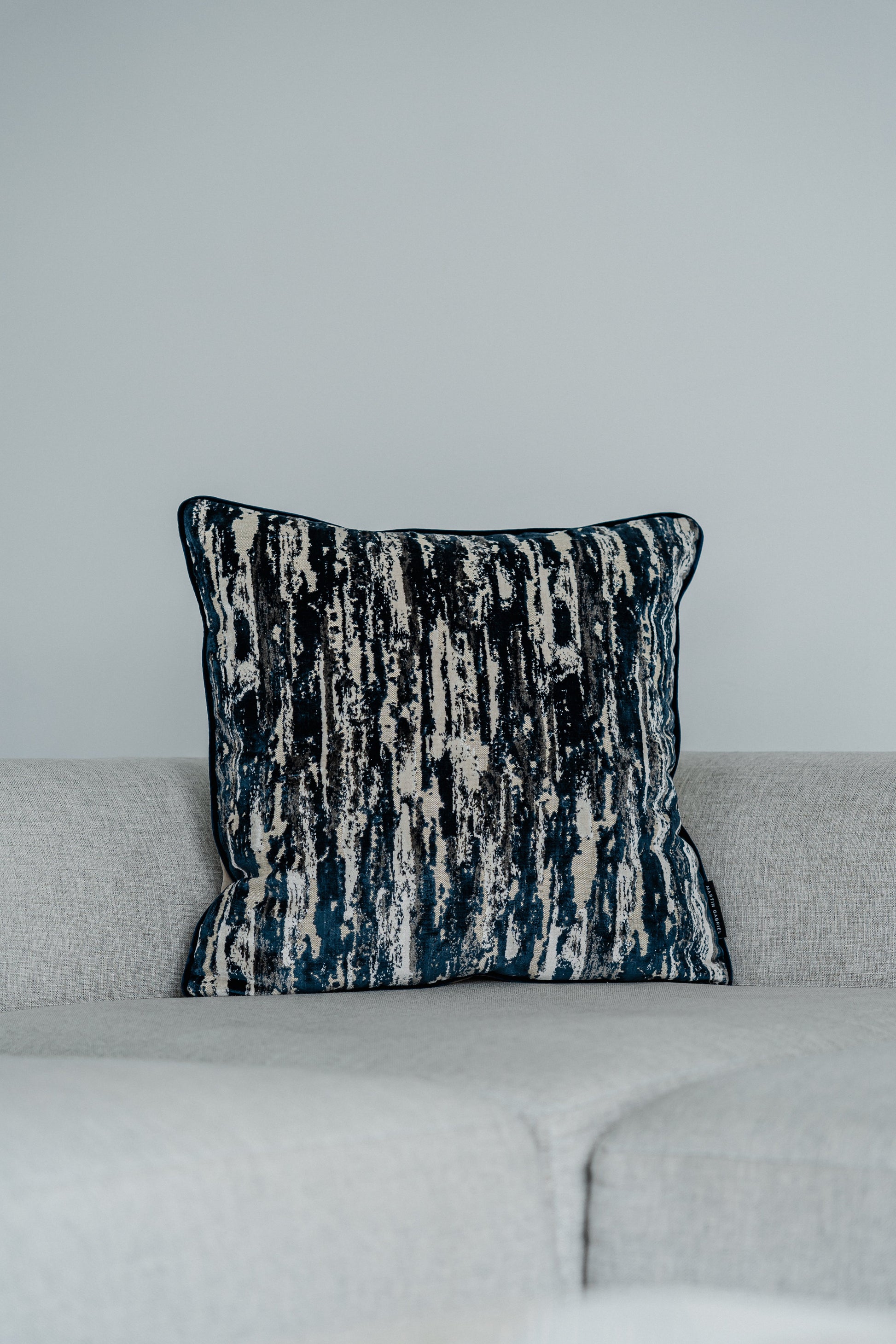Dekokissen Cascade Blue 60x60 cm auf hellgrauem Sofa – Vorderansicht
