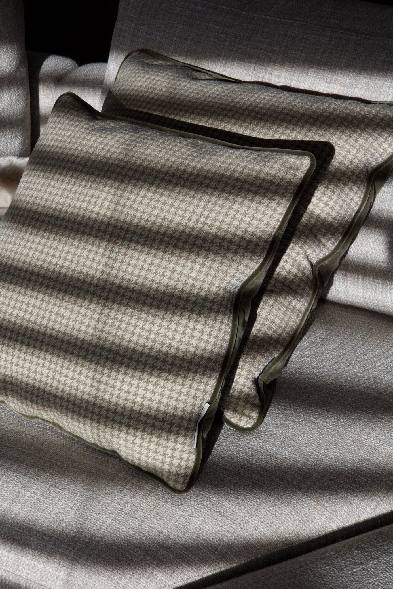 Martin Gabriel Indoor Kissen Chalet Kollektion Modell Cervino verde mit einem deznt Tannengrünen Hahnetritt und in der Rückseite ein altgrünes Velour auf einem Sofa mit einem zweiten Kissen in Ambeinte stimmung mit schatten 