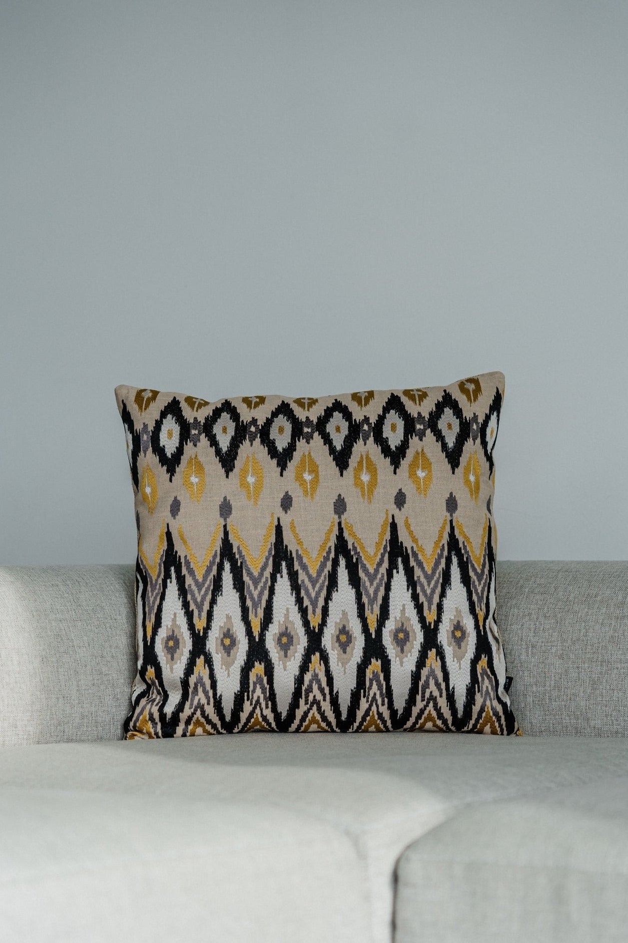 Martin Gabriel deko kissen modell Ikato mit karomuster in weiss geld´b und beige besticktes. textil auf hellgrauen sofa 