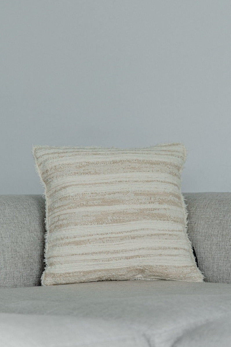 Martin Gabriel Designkissen modell Livorno aus strukturierter Naturtextilie mit horizontalen Streifen in beige und Naturtönen auf grauem Sofa