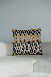 Designer-Dekokissen im Ikato-Muster in Beige, Gelb und Schwarz von Martin Gabriel, dekoriert auf hellem Sofa im Wohnzimmer.
