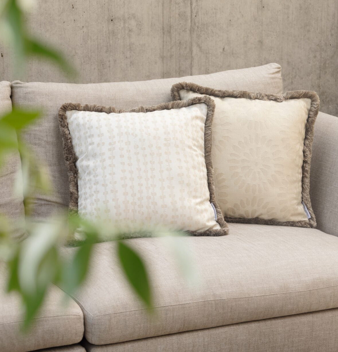 Martin Gabriel - Modell Chiasso mit Fransen auf einem Sofa auf einer Terrasse in beigetönen mit einem weietren Kissen in dem selben farbton 